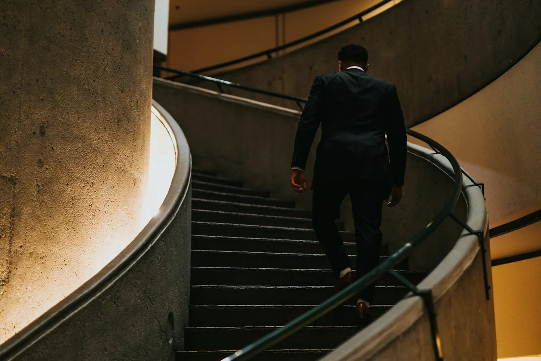 Hombre con traje subiendo una escalera de caracol