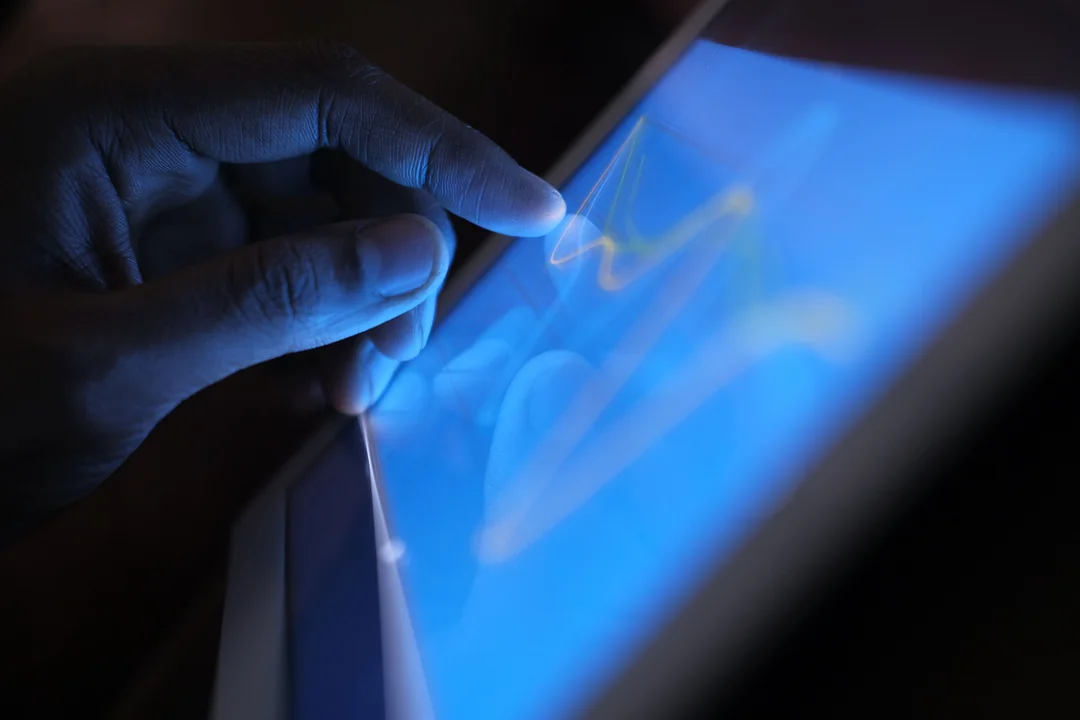 Mano sobre una tableta con un gráfico iluminado en azul