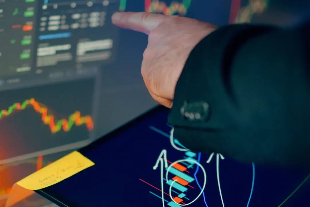 Profesional señalando gráficos de datos en una pantalla y una tableta