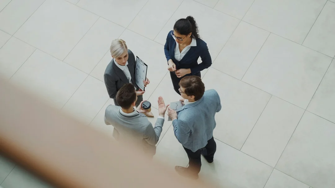 Cuatro profesionales conversando en el vestíbulo de una oficina